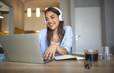 微笑的女学生戴着无线耳机和skype老师在线学习